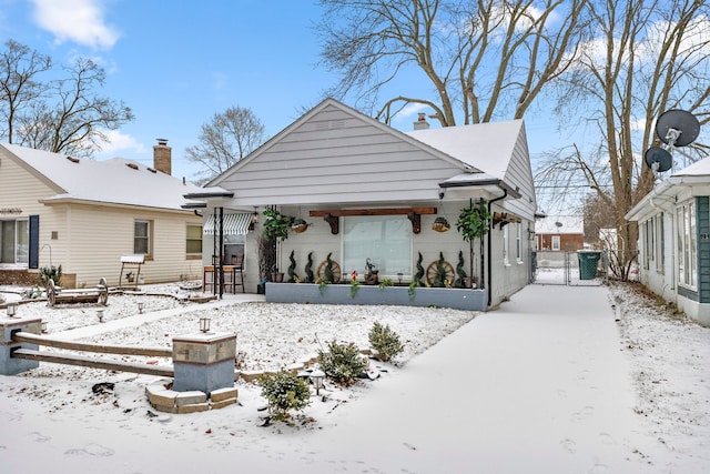 snow covered back of property featuring a gate