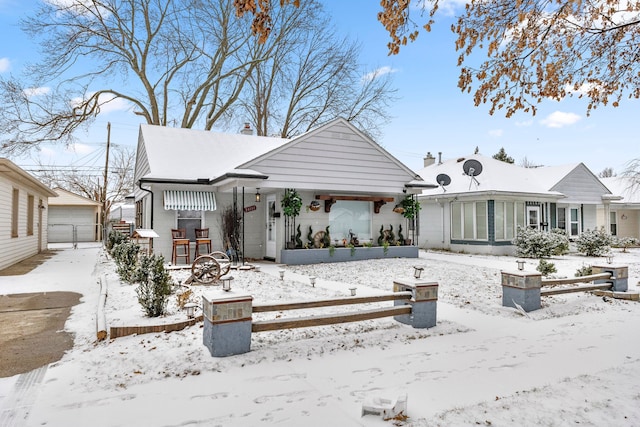 snow covered back of property with a detached garage and covered porch