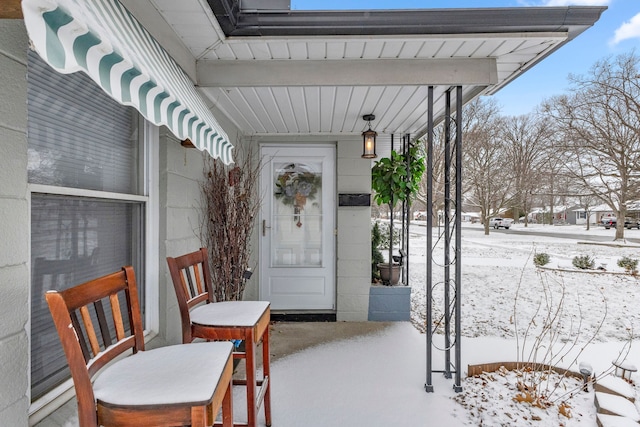 snow covered property entrance with a porch