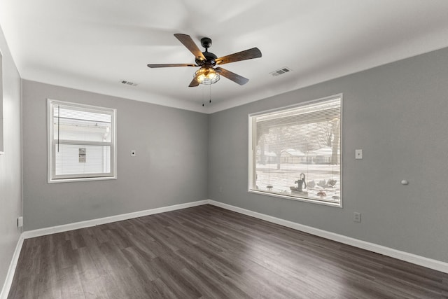 unfurnished room featuring visible vents, baseboards, dark wood-type flooring, and a ceiling fan