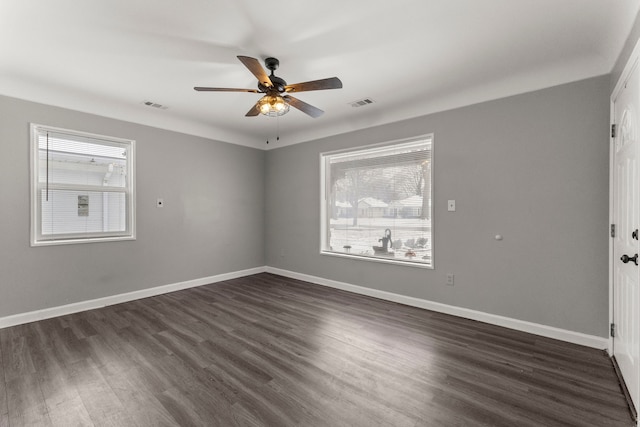 empty room with visible vents, baseboards, and dark wood-style flooring