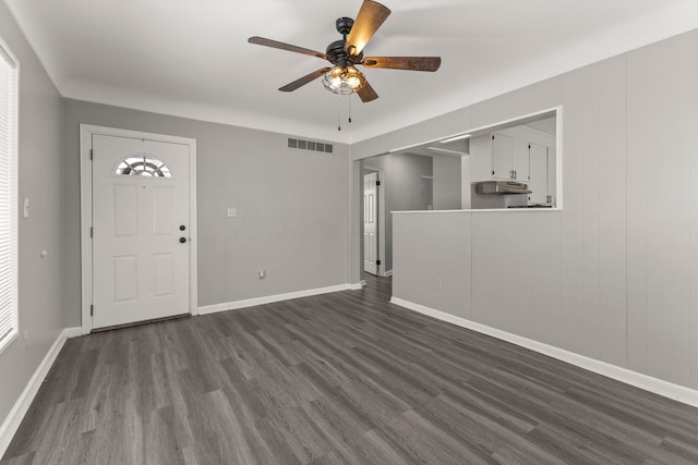 unfurnished living room with ceiling fan, visible vents, baseboards, and dark wood finished floors