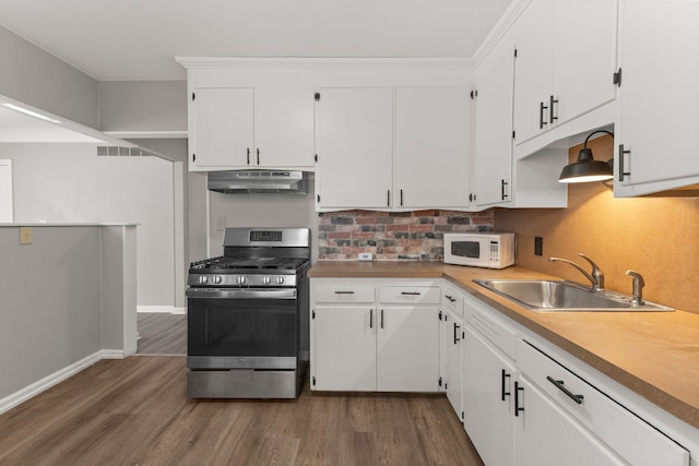 kitchen featuring white microwave, visible vents, under cabinet range hood, stainless steel gas range, and a sink