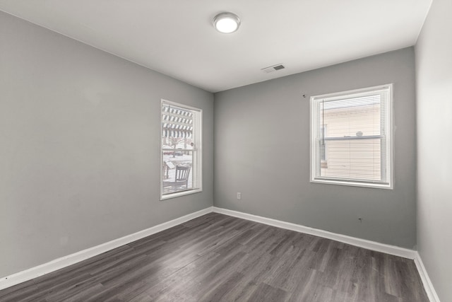 unfurnished room with dark wood finished floors, visible vents, and baseboards