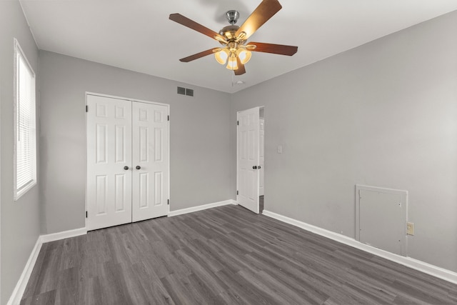 unfurnished bedroom featuring a ceiling fan, baseboards, visible vents, dark wood-style flooring, and a closet