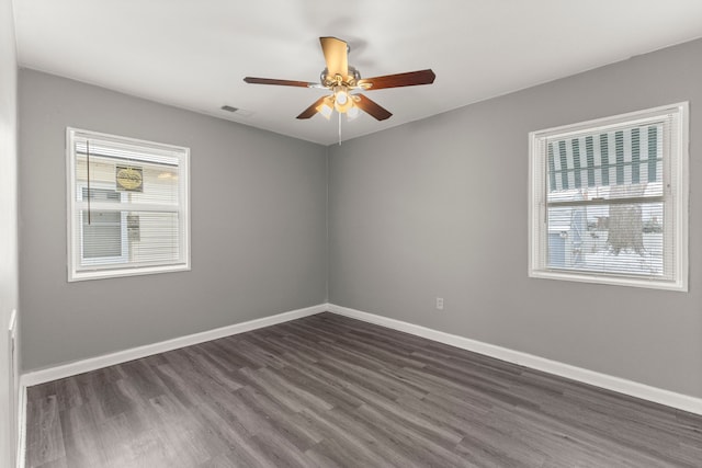 unfurnished room featuring a ceiling fan, visible vents, dark wood-style floors, and baseboards