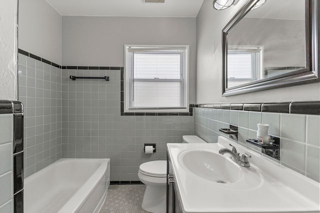 full bath featuring a wealth of natural light, tile patterned floors, toilet, and tile walls