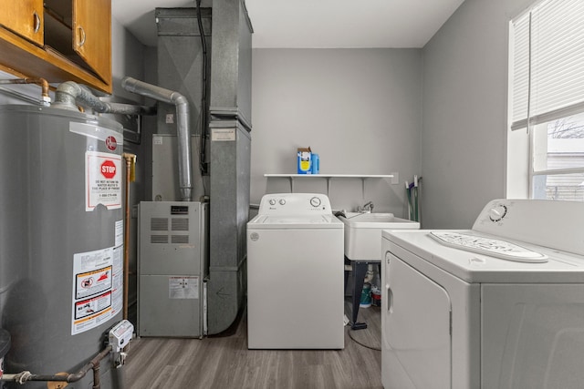 clothes washing area with separate washer and dryer, wood finished floors, cabinet space, and water heater