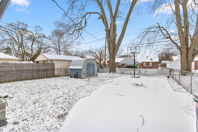 yard layered in snow with an outbuilding, a residential view, a storage unit, and a fenced backyard