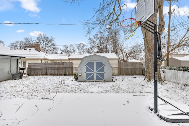 yard layered in snow with an outbuilding, a storage shed, and a fenced backyard