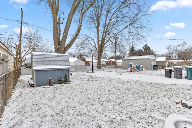 snowy yard with a residential view, a storage shed, a fenced backyard, and an outdoor structure