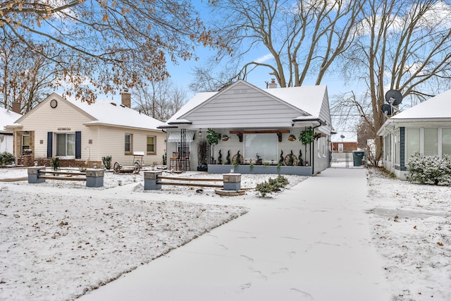 snow covered property with a chimney and a gate