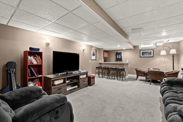 living area featuring a bar, a paneled ceiling, baseboards, and carpet floors