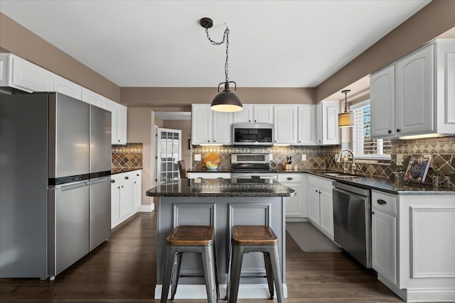 kitchen featuring white cabinets, appliances with stainless steel finishes, a kitchen island, and a sink