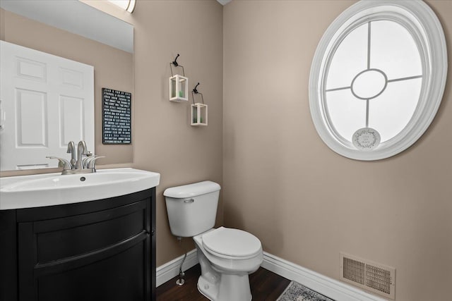 bathroom featuring vanity, wood finished floors, baseboards, visible vents, and toilet