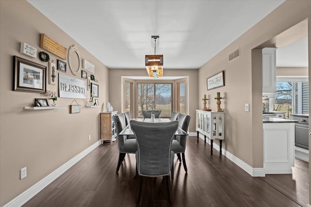 dining space with dark wood finished floors, plenty of natural light, baseboards, and visible vents