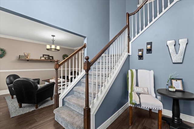 staircase with baseboards, a notable chandelier, wood finished floors, and crown molding