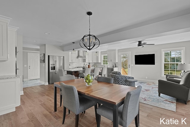 dining area with ceiling fan with notable chandelier, light wood-type flooring, and baseboards