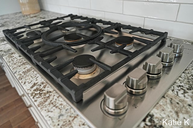 interior details featuring dark wood finished floors, decorative backsplash, and stainless steel gas stovetop