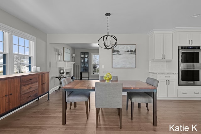 dining room with light wood-style flooring, baseboards, a wealth of natural light, and a chandelier