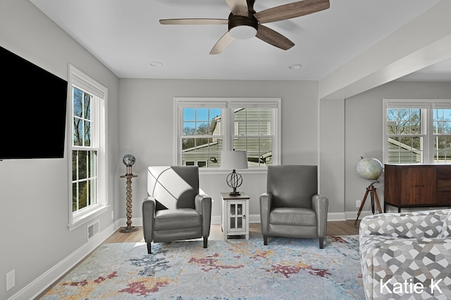 sitting room featuring visible vents, baseboards, wood finished floors, and a ceiling fan