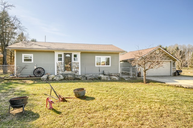 ranch-style home featuring a garage, an outdoor fire pit, a front lawn, and fence