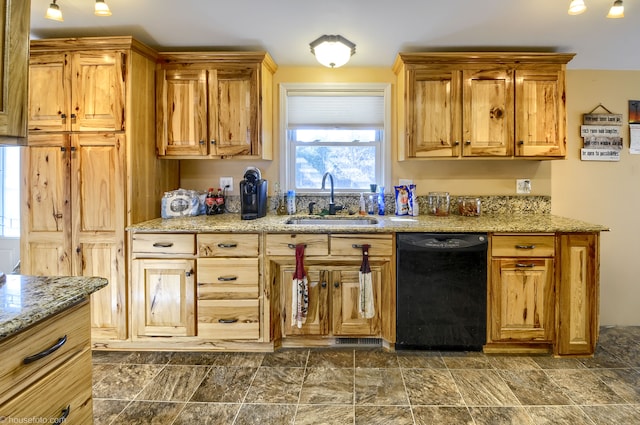 kitchen with light stone countertops, black dishwasher, and a sink