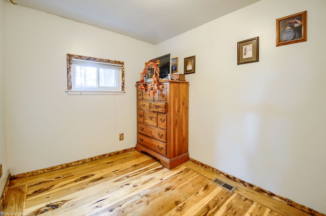 spare room featuring light wood-type flooring, visible vents, and baseboards