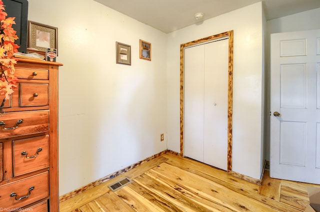 bedroom with baseboards, visible vents, a closet, and light wood-type flooring