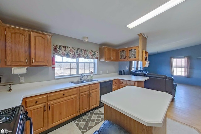 kitchen featuring a healthy amount of sunlight, lofted ceiling, a sink, black appliances, and light countertops