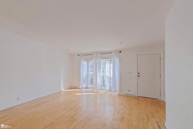 unfurnished room with baseboards and light wood-style floors