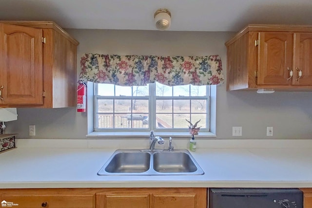 kitchen with dishwashing machine, brown cabinetry, light countertops, and a sink