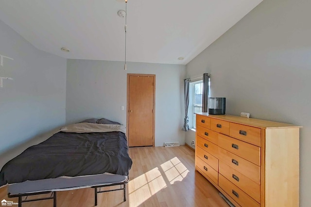 bedroom featuring vaulted ceiling, light wood-style flooring, and visible vents