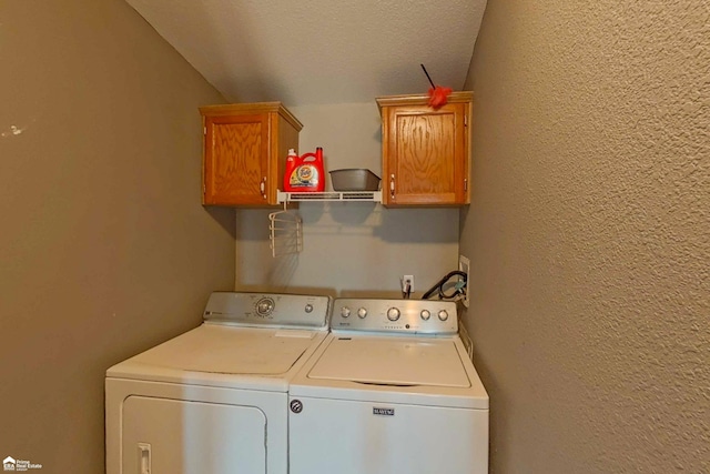 laundry area with washer and clothes dryer, cabinet space, a textured ceiling, and a textured wall