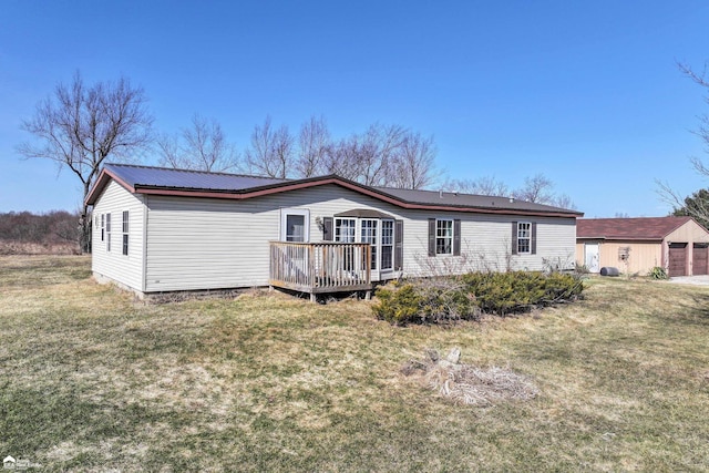 back of property featuring an outbuilding, a yard, metal roof, and a wooden deck