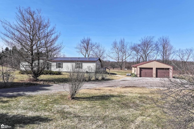 view of front of home with metal roof, a detached garage, an outbuilding, and a front lawn