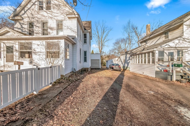 view of home's exterior featuring a sunroom and dirt driveway