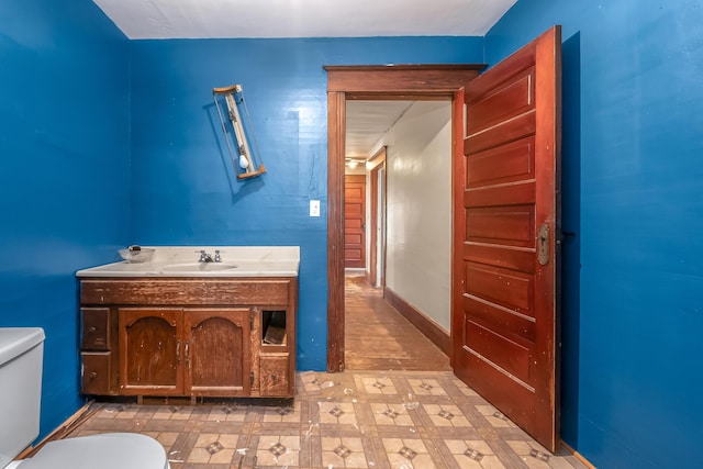 half bathroom featuring vanity, tile patterned floors, toilet, and baseboards