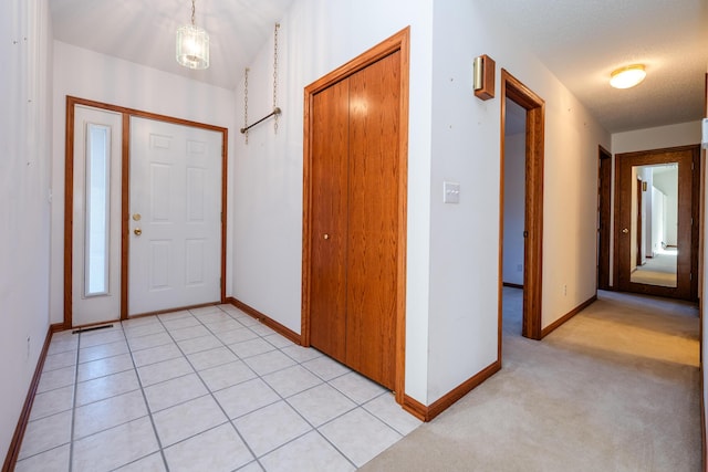 entryway with light tile patterned floors, a textured ceiling, and baseboards