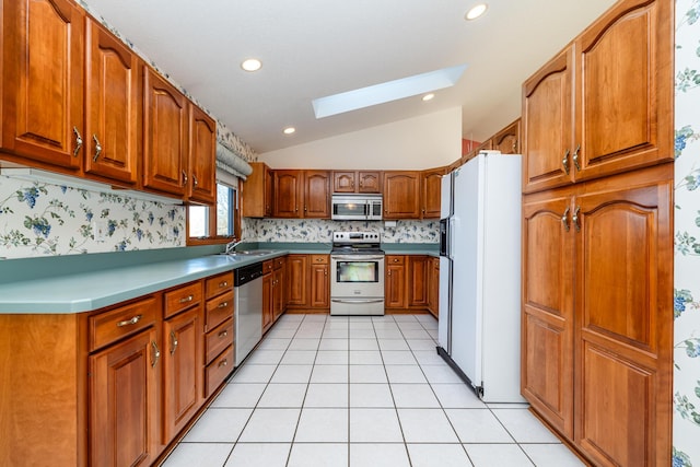 kitchen featuring backsplash, brown cabinets, vaulted ceiling with skylight, light tile patterned flooring, and stainless steel appliances