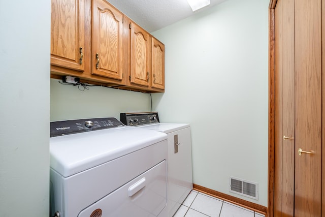 clothes washing area with light tile patterned floors, visible vents, baseboards, cabinet space, and washing machine and dryer