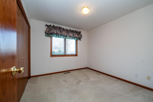 unfurnished bedroom with visible vents, light carpet, a textured ceiling, a closet, and baseboards