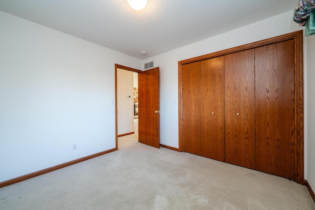 unfurnished bedroom with visible vents, baseboards, carpet, a closet, and a textured ceiling