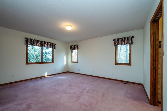 empty room featuring visible vents, baseboards, carpet, and a textured ceiling