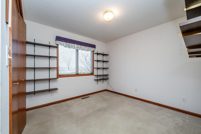 unfurnished room with visible vents, a textured ceiling, baseboards, and carpet floors