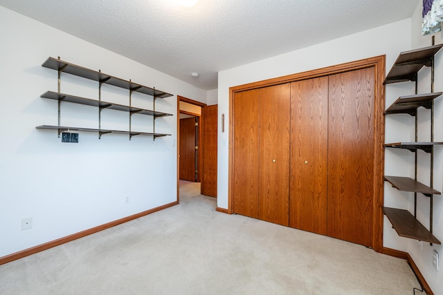 unfurnished bedroom featuring a closet, baseboards, carpet, and a textured ceiling