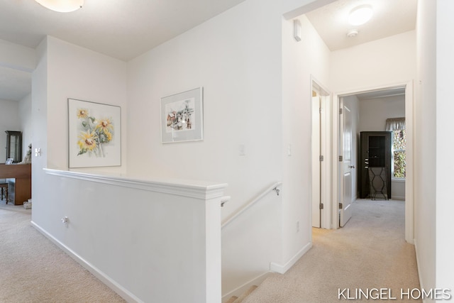 corridor featuring baseboards, an upstairs landing, and carpet flooring