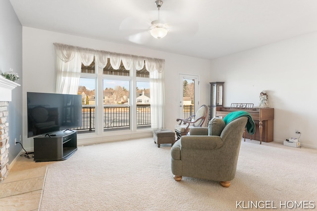 living area with baseboards, ceiling fan, and carpet flooring