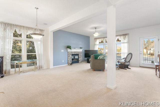 carpeted living area featuring a glass covered fireplace, baseboards, and ceiling fan