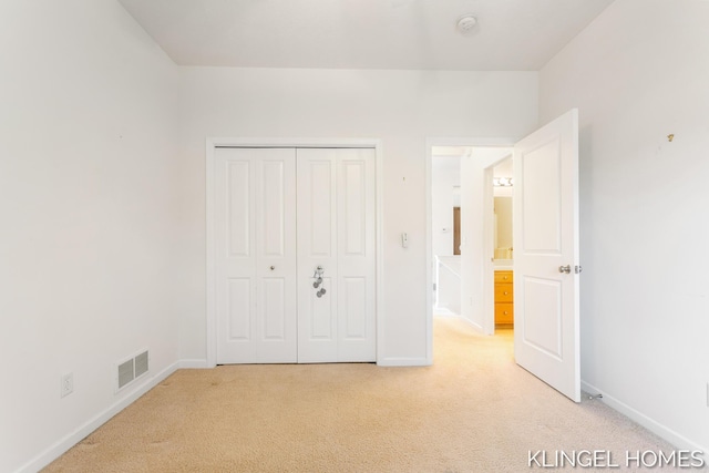 unfurnished bedroom with baseboards, visible vents, a closet, and light carpet